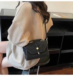 Detail view of black vintage crossbody bag with white stitching and gold metal clasp