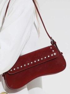 Chic burgundy underarm bag with silver studs and sleek shoulder strap on white blazer