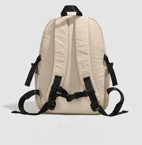 Detail of the ergonomic padded shoulder straps and adjustable chest buckle on the beige backpack