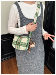 Detail of green plaid plush crossbody bag with orange button and leopard hat bear charm