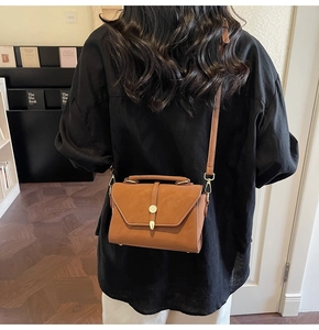 Brown vintage leather crossbody bag with gold buckle shown on shoulder for daily use