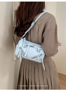 Detailansicht der hellblauen Leder-Baguette-Tasche mit Nieten und Reißverschlüssen am Model