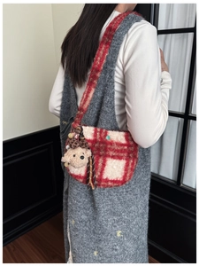 Detail showing plush red checkered shoulder bag with cute bear charm and tassel