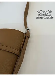 Detail of adjustable shoulder strap with silver metal buckle on brown leather bucket bag