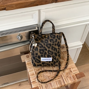 Détail du sac à bandoulière léopard sur chaise en bois avec pendentif en forme de cœur