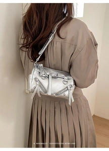 Detailansicht einer silbernen Umhängetasche im Retro-Look mit Schnallen am Model