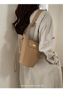 Détail de la texture cuir kaki et boucle dorée sur le sac seau au style rétro