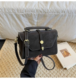 Close-up of vintage brown leather handbag featuring white contrast stitching and gold buckle