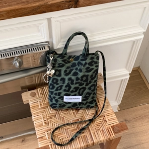 Détail du sac en toile léopard vert avec pendentif cœur en métal et bandoulière