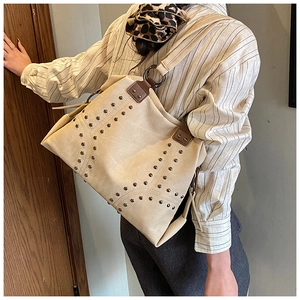Detail of vintage beige canvas tote bag with metal rivets and brown leather strap handles
