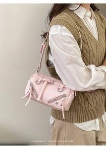 Detailansicht der rosa Retro-Umhängetasche mit Nieten und Schnallen auf beigem Pullover