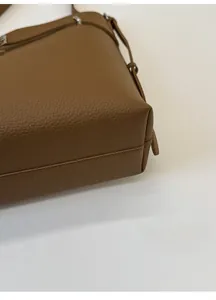 Close-up of the wide bottom design on a brown pebbled leather shoulder bucket bag