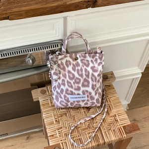 Gros plan du mini sac en toile léopard avec breloque en métal sur un tabouret