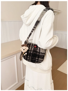 Detail of plush checkered crossbody bag with cute teddy bear charm on model shoulder