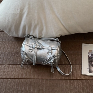 Draufsicht der silbernen metallischen Zylindertasche mit Reißverschlüssen auf Holzboden
