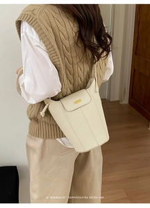 Détail du sac seau en cuir blanc crème avec finitions dorées et texture grainée fine