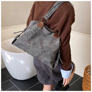Detail of vintage grey tote bag with silver studs and brown leather straps on a model
