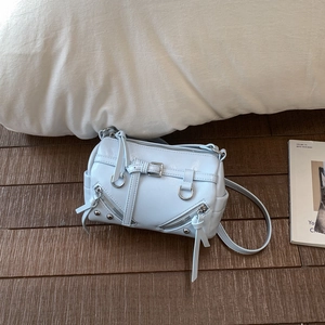 Detailansicht der hellblauen Zylindertasche mit silbernen Reißverschlüssen auf Holzboden