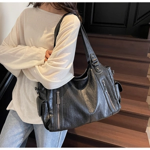 Detailed side view of large black pleated PU leather tote bag with silver zippers