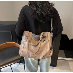 Sac fourre-tout marron rétro avec boucle métallique porté par un mannequin dans un cadre épuré