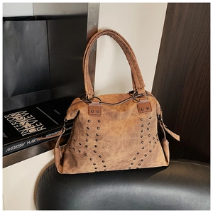 Close-up of vintage brown tote bag featuring decorative metal rivets and distressed leather