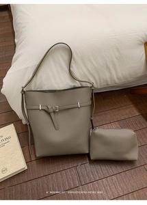 Close-up of grey leather bucket bag set with matching zipper pouch on a wooden floor