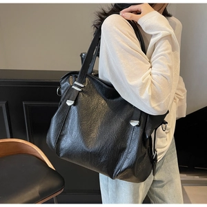 Detail shot of the black leather tote bag showing high-quality texture and silver hardware