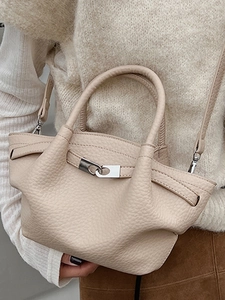 Sac seau chic en cuir beige avec boucle argentée et bandoulière porté par un mannequin
