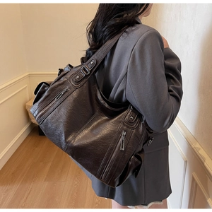 Detail view of large dark brown retro hobo bag with multiple silver zippers and rivets