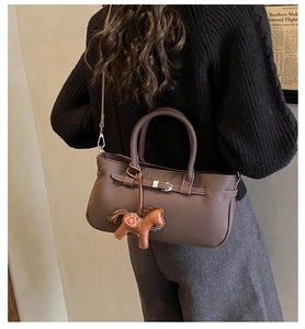 Detail of dark coffee leather shoulder bag with matching pony charm and metal buckle