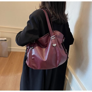 Gros plan sur la texture du sac cabas en similicuir bordeaux avec détails en métal argenté