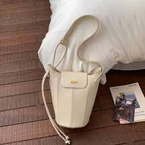Détail du sac seau en cuir grainé blanc cassé avec ferrures dorées et cordon de serrage