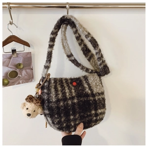 Detail of plush checkered crossbody bag with fuzzy bear charm and soft textures