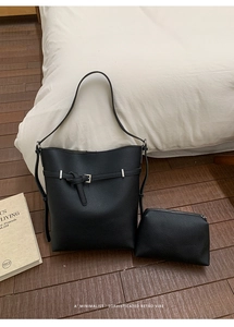 Detail of black lychee grain leather bucket bag and pouch set on a wooden floor