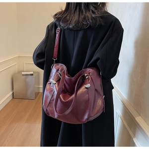 Détail du sac cabas en cuir bordeaux avec boucles argentées et bandoulière large