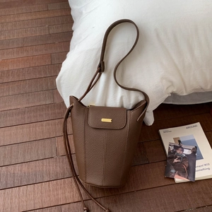 Détail du sac seau en cuir grainé marron foncé avec boucle métallique dorée élégante