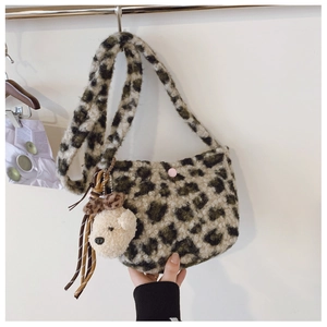 Close-up of leopard print plush shoulder bag with a pink button and cream teddy bear charm