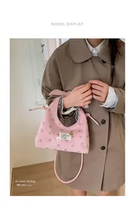 Detail of pink polka dot bag featuring a cat logo label and black striped lining texture