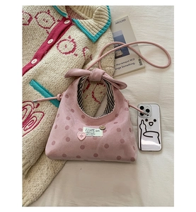Macro detail of pink polka dot bag featuring heart button and bow handle texture