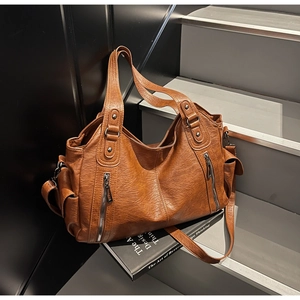 Détail d'un sac cabas vintage en cuir marron grainé posé sur des marches sombres