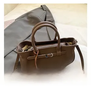 Detail of dark brown litchi leather handbag with twin handles and horse charm