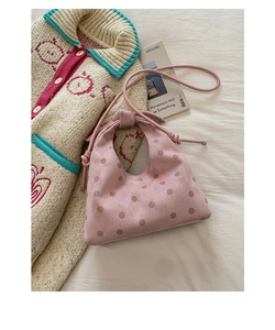 Detail of pink polka dot handbag with knotted handle and shoulder strap on beige knitwear