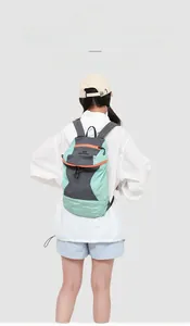 Rear view of model wearing a lightweight light green and grey hiking backpack with orange zippers