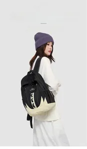 Détail latéral du sac à dos contrasté noir et beige avec poches en filet et étiquettes