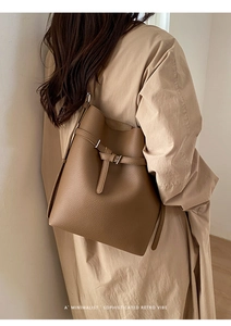 Minimalist brown pebbled leather bucket bag styled with a classic beige trench coat
