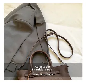 Detailed view of the adjustable shoulder strap and leather texture on a brown handbag