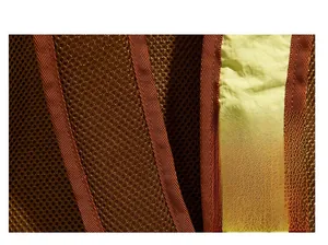 Gros plan sur la maille respirante marron et la sangle jaune d'un sac à dos de randonnée