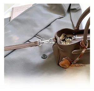 Detail of silver spring hook and stitching on brown leather handbag with horse charm