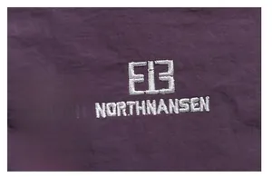 Detailed macro view of white embroidered brand logo on deep purple fabric texture