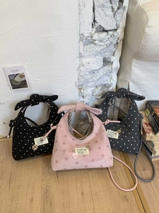 Detailed view of three polka dot bow handbags in black, pink, and dark grey tones